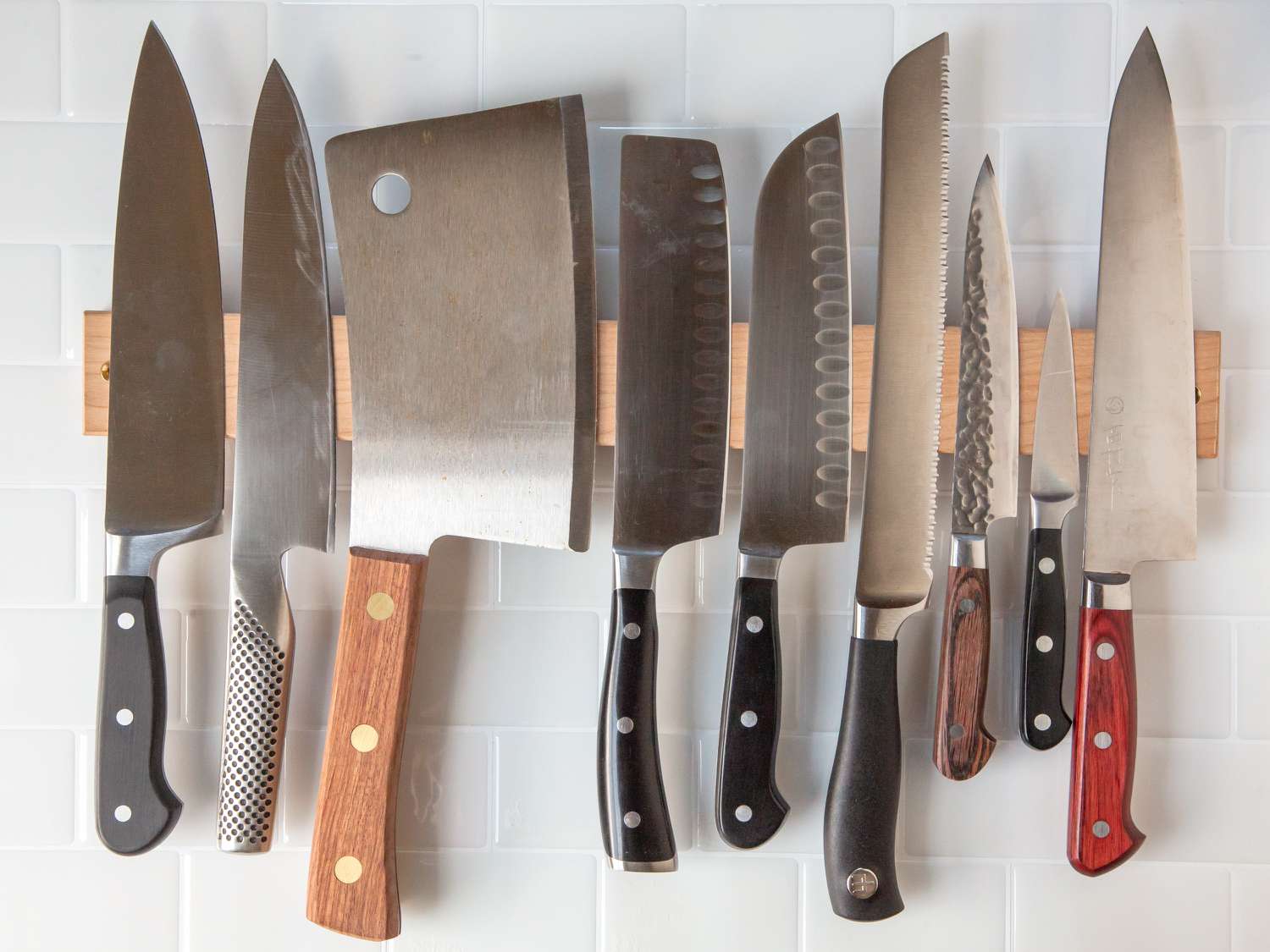 An assortment of knives on a wooden knife strip