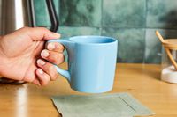 A person picking up a blue coffee mug.
