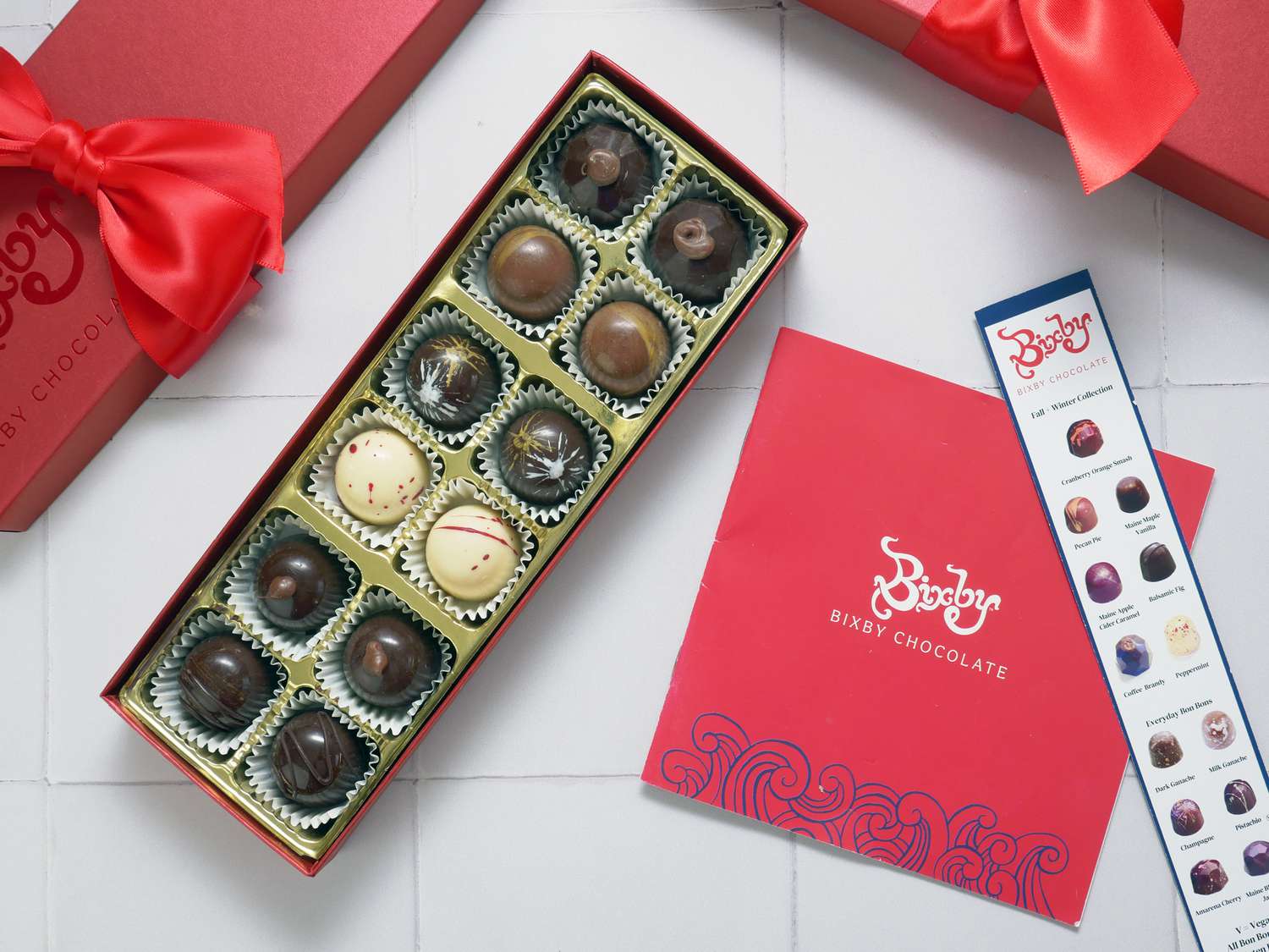 bixby chocolates with the lid off and the information cards next to the boxes