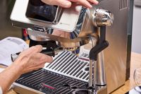 A person adds ground espresso to the De'Longhi La Specialista Touch Espresso Machine