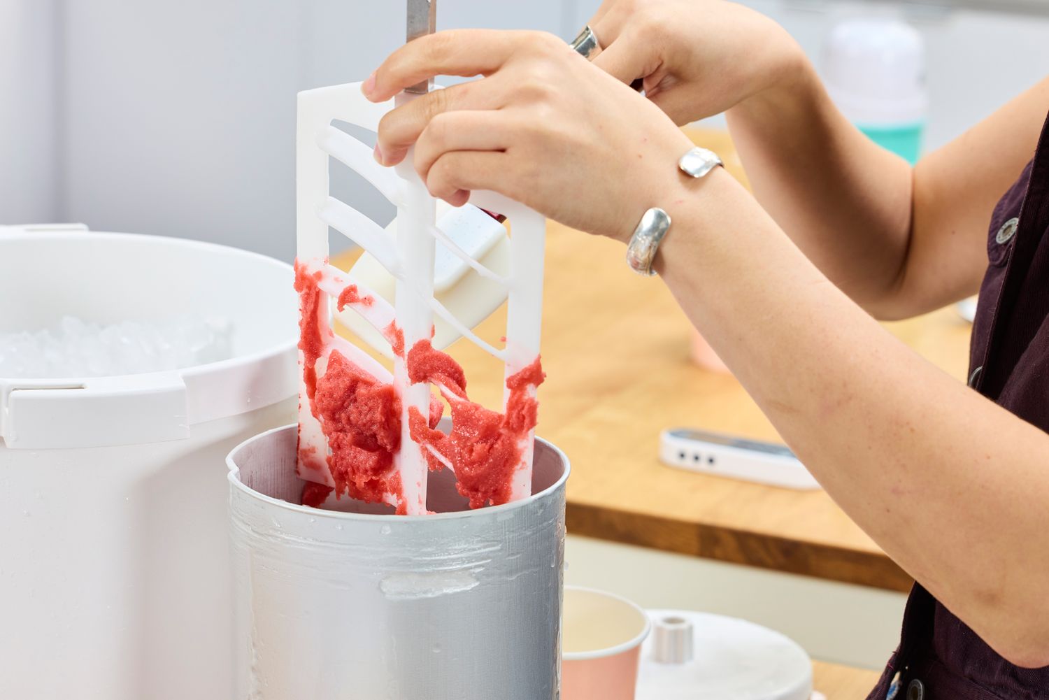 A person using a spatula to remove ice cream from the Hamilton Beach Automatic Ice Cream Maker