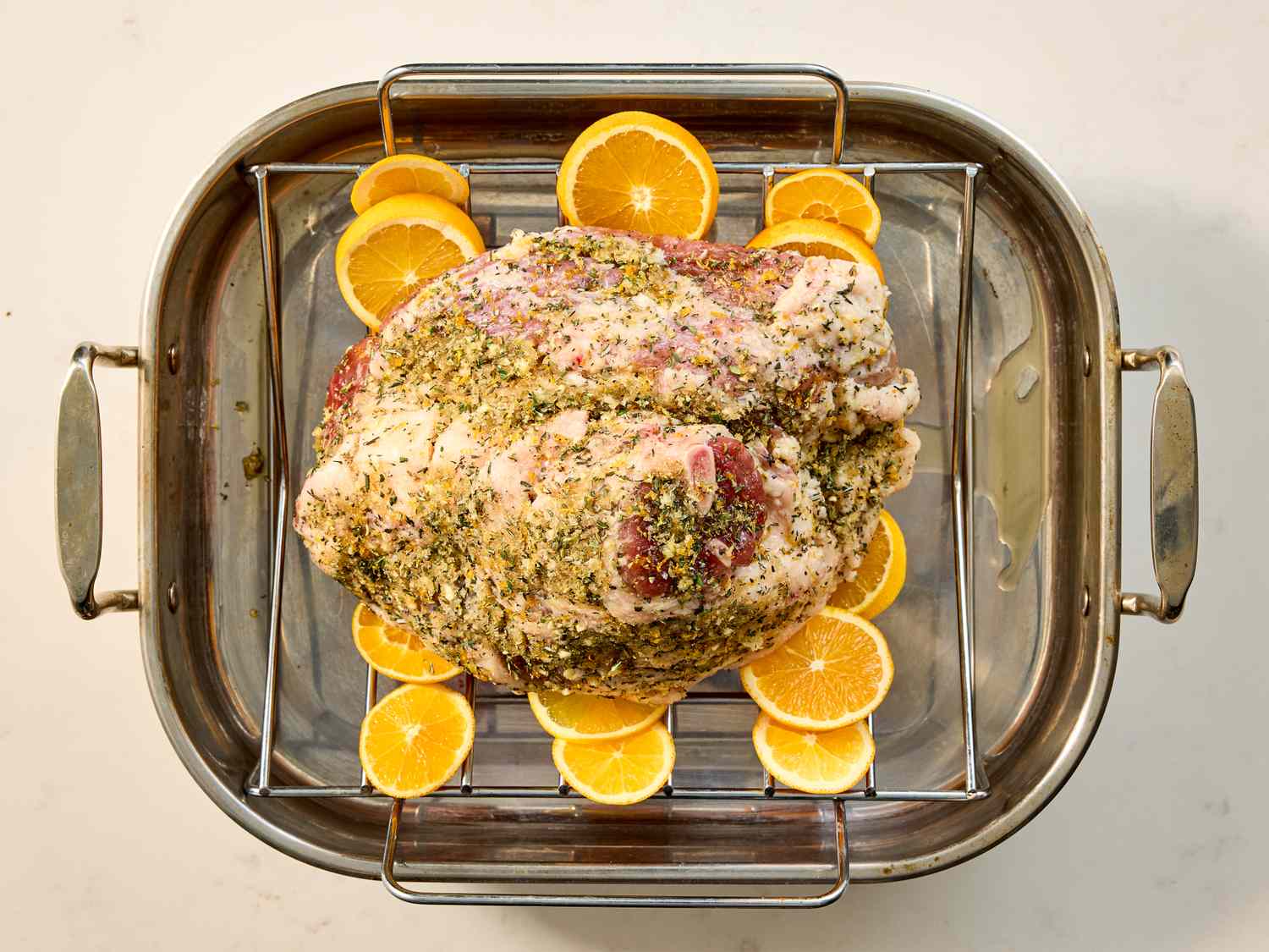 Seasoned ham placed in a roasting pan garnished with orange slices around the meat