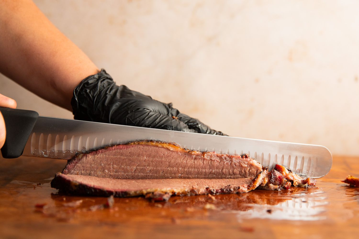 A person slicing meat using the Victorinox Fibrox Pro Slicing Knife
