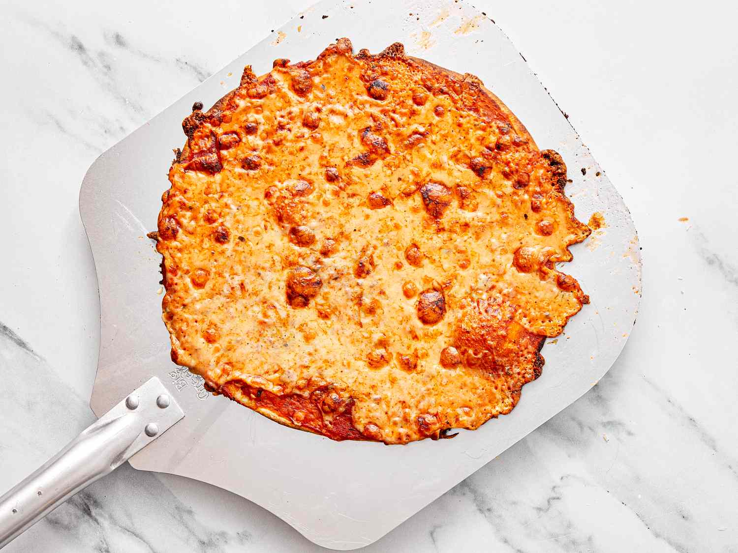 A cooked St Louisstyle pizza resting on a pizza peel