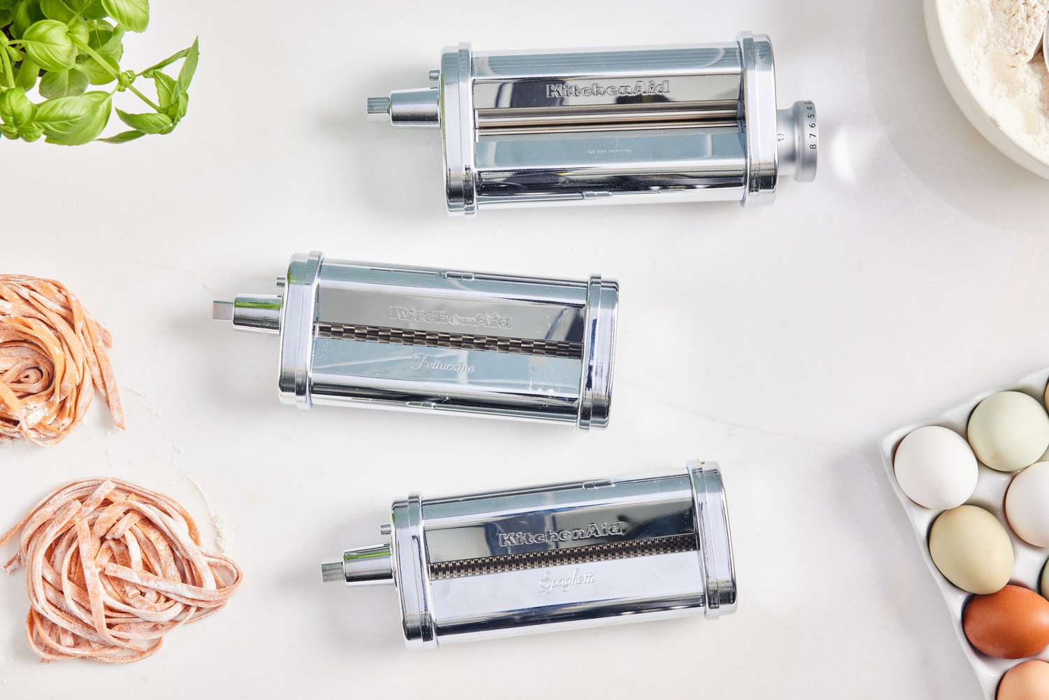 Three attachments of the KitchenAid 3-Piece Pasta Roller & Cutter Attachment Set displayed on white surface 