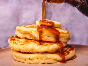 Side view of pouring syrup on pancakes