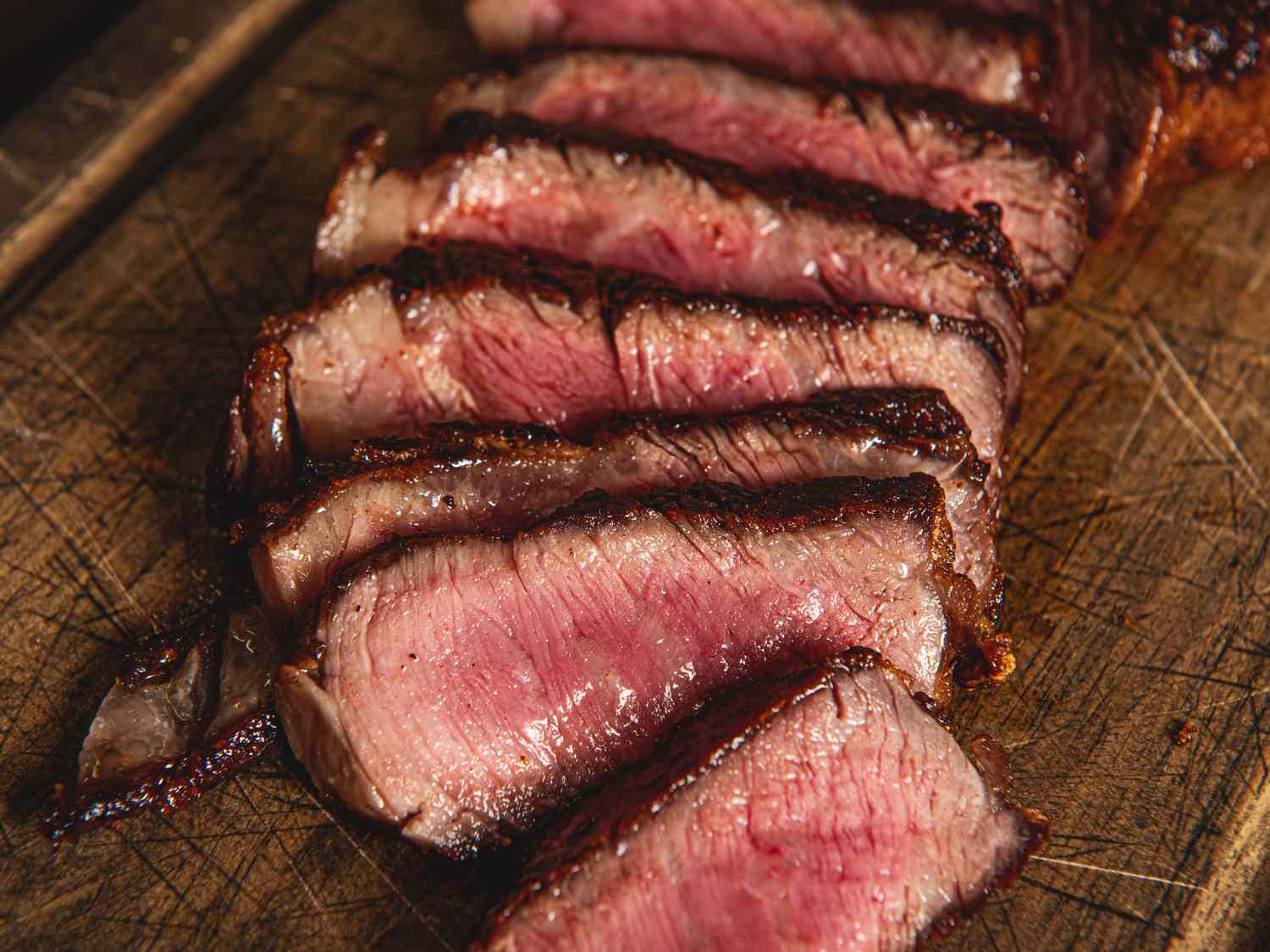 Slices of cooked steak arranged on a wooden surface