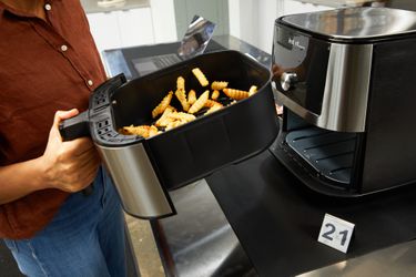 A person tossing fries in the Instant Pot Vortex Plus 6-Quart 6-in-1 Air Fryer's basket