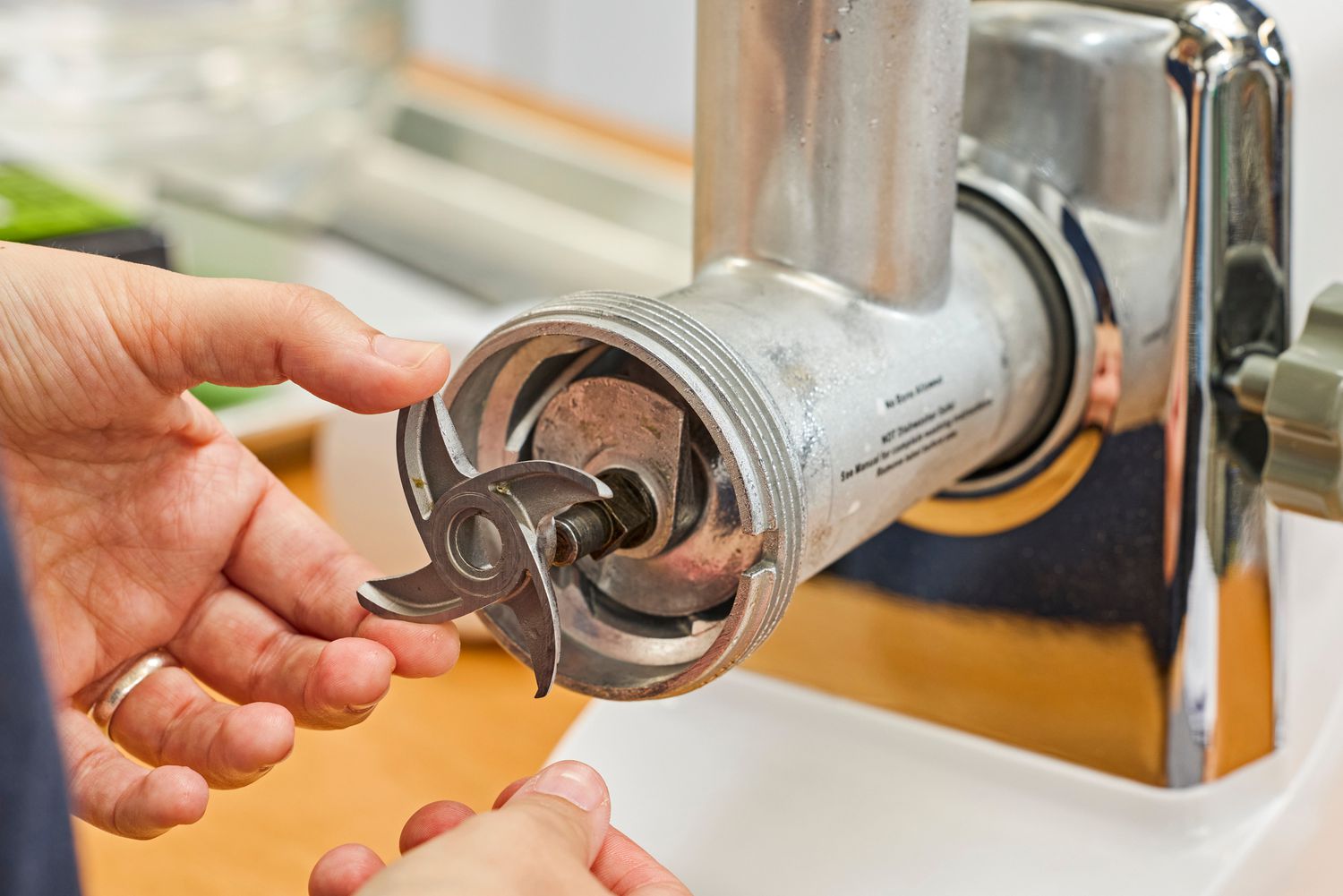 Person fixing grinding blade of STX International Turboforce Classic 3000 Series Electric Meat Grinder & Sausage Stuffer