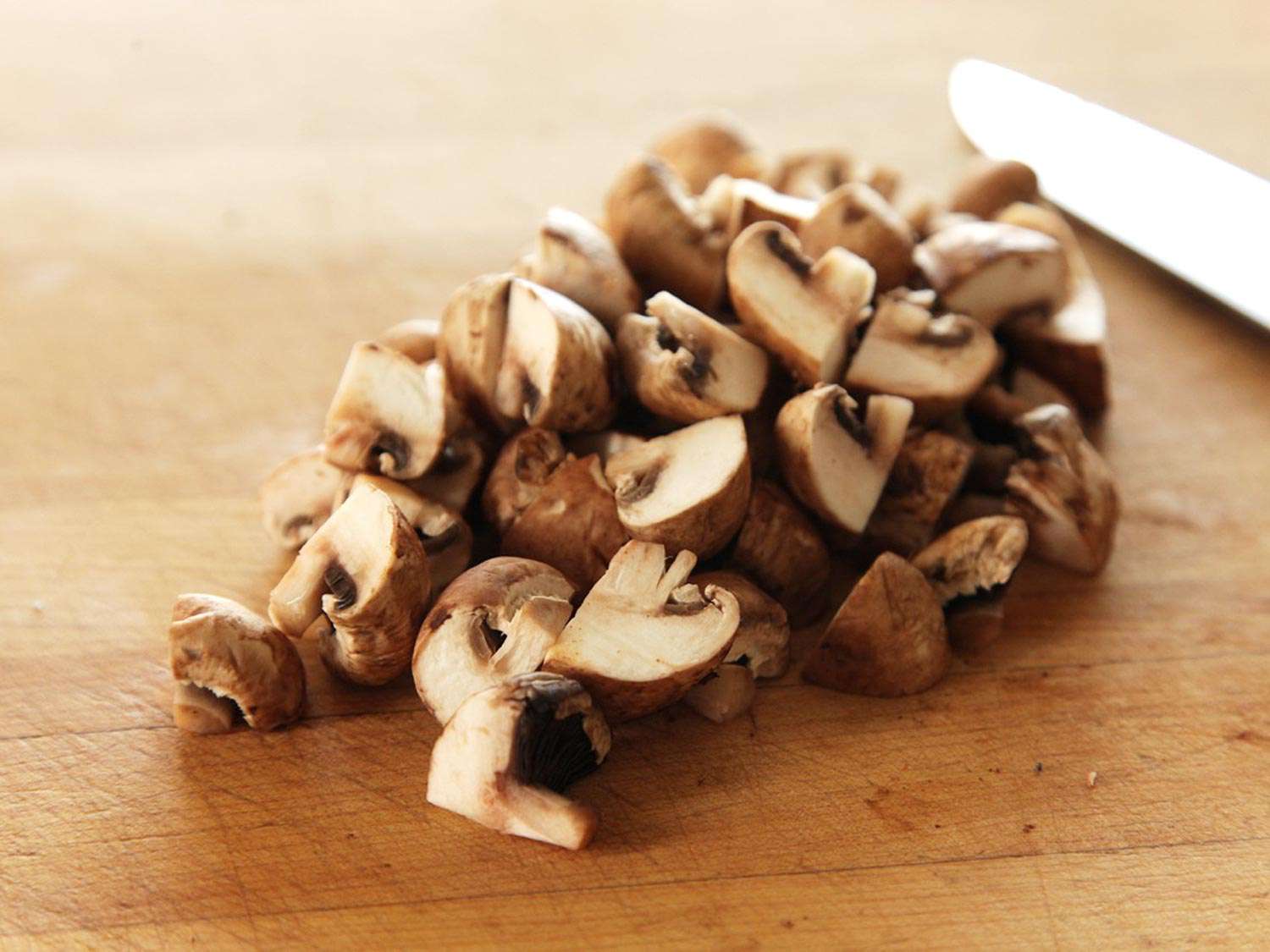 Quartering button mushrooms for green bean dish.