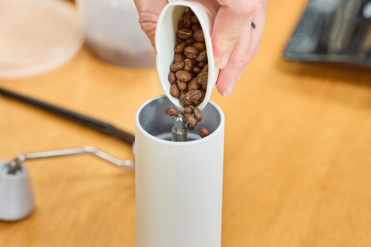 A person pours coffee beans into the Timemore C2 Max Manual Grinder