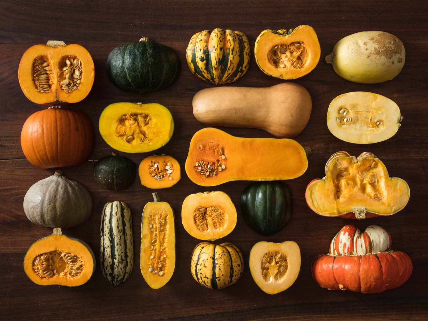 A collection of different varieties of winter squash, displayed cut-side down and cut-side up