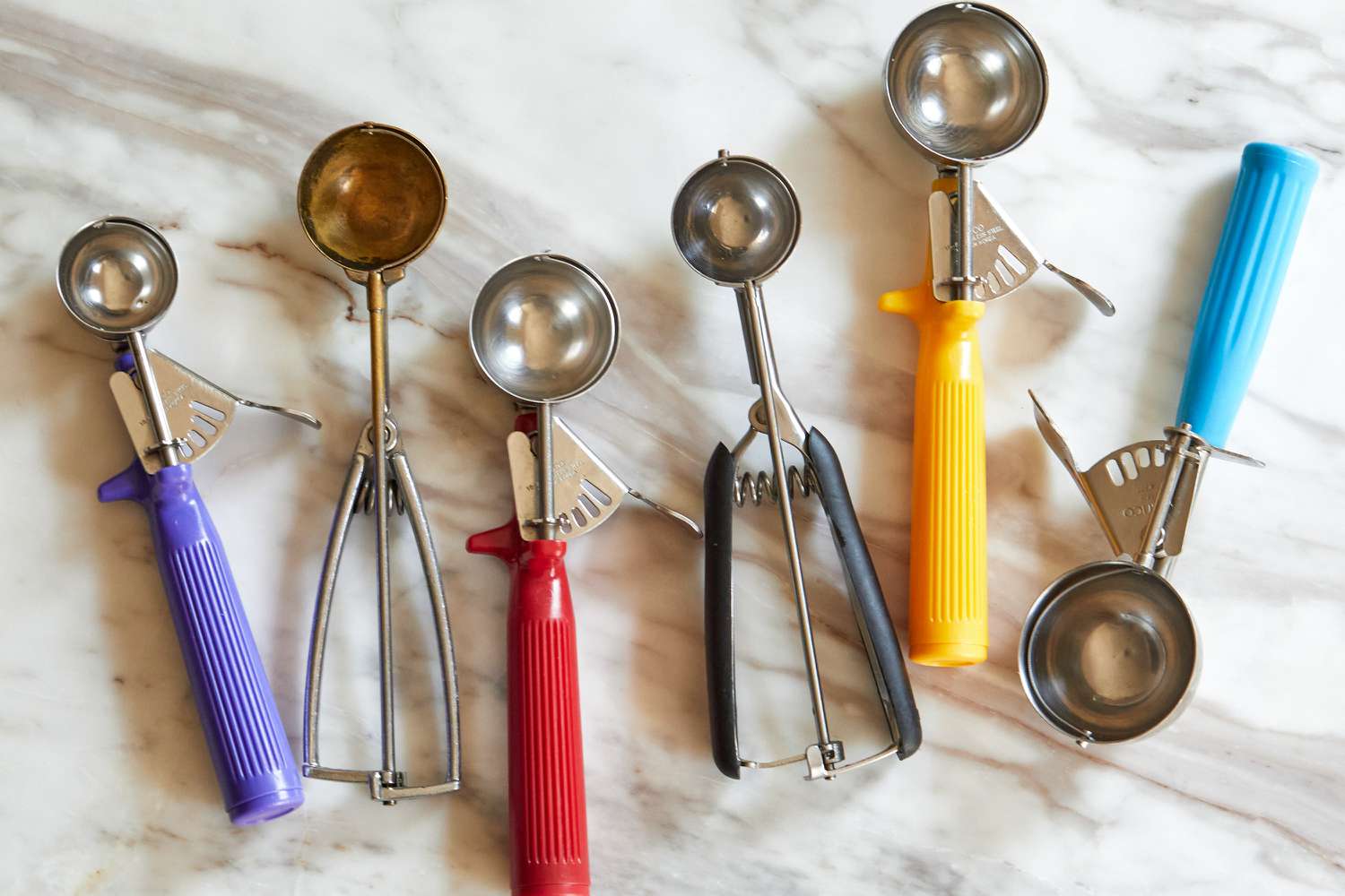 Six portion scoops on a marble countertop