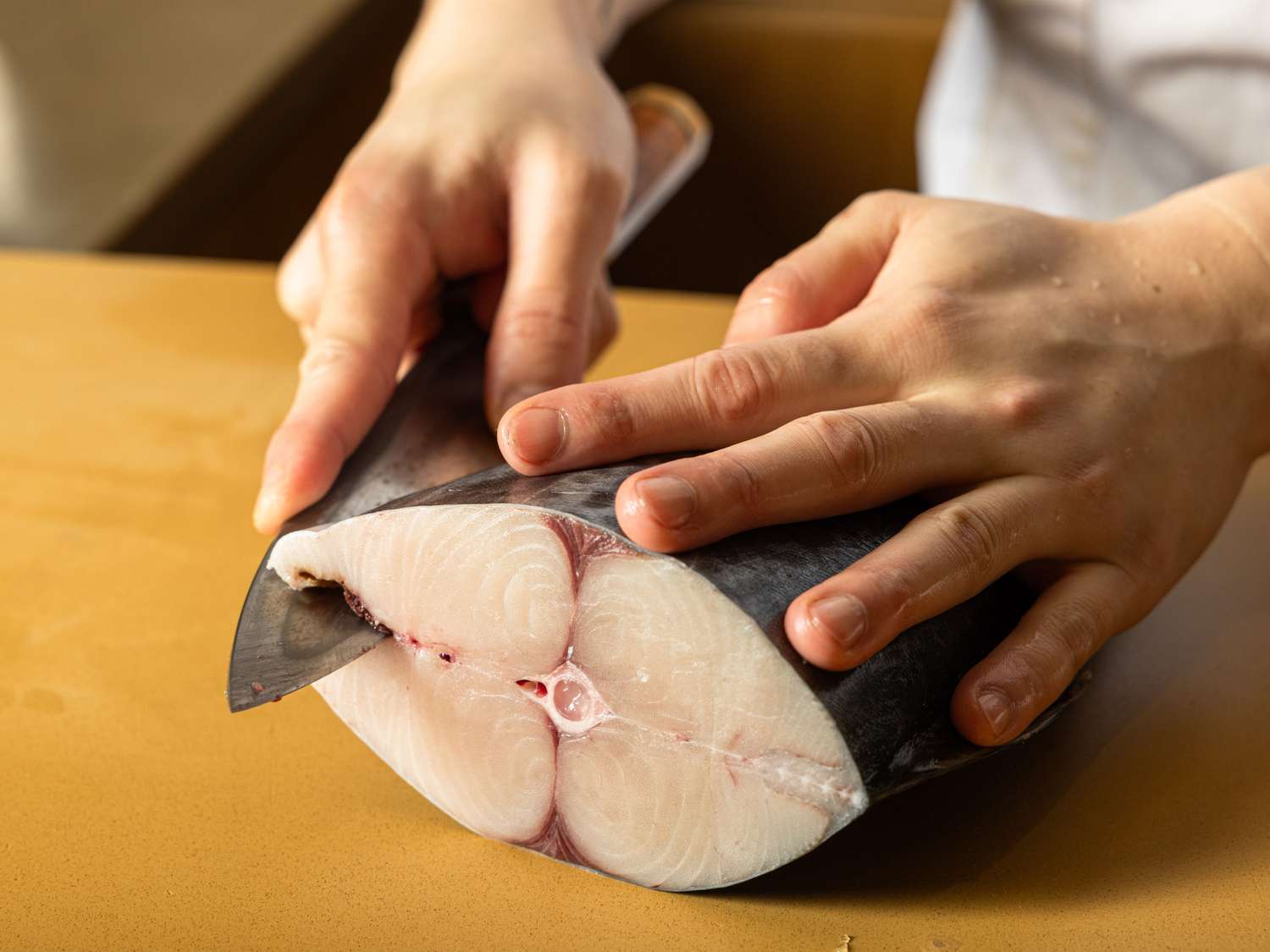 A person slicing a fish fillet with a knife