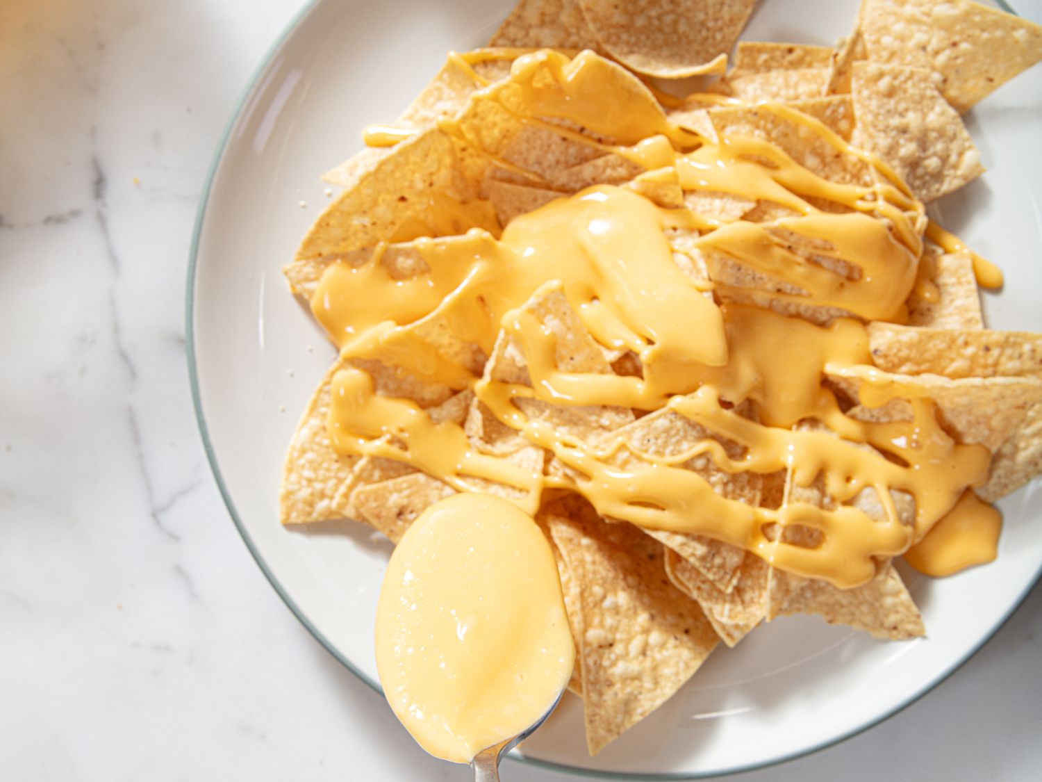 Cheesy nachos on a white plate.