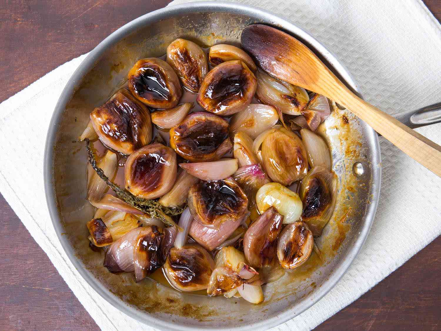 Overhead shot of a saute pan with caramelized roasted shallots in a buttery glaze