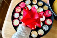 The Dandelion Chocolate Advent calendar, opened, with a hand holding its bow above it