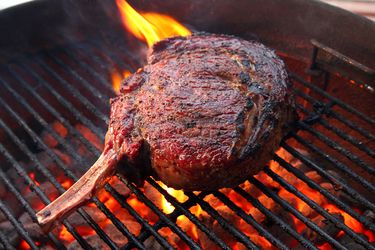 A bone-in ribeye steak on a hot grill.