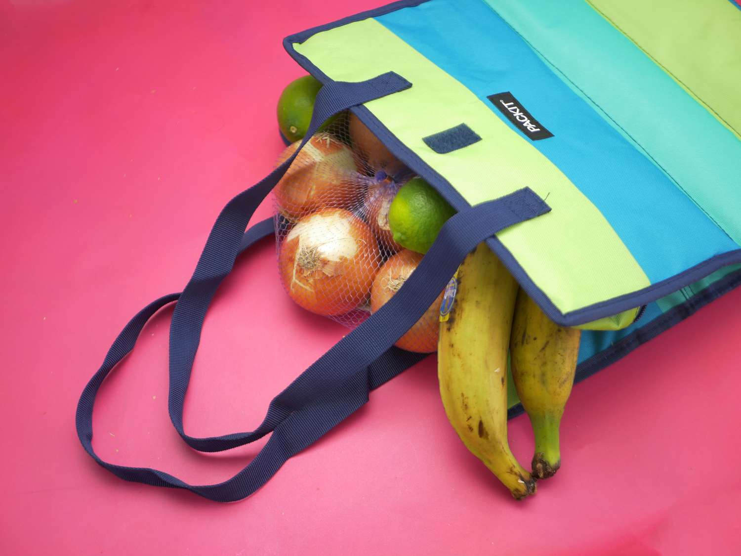 Packit grocery bag on its side with plantains, onions, and limes spilling out
