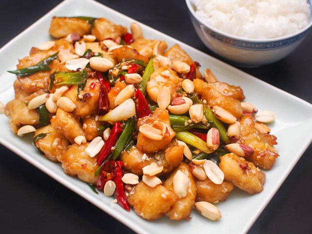 Closeup of kung pao fish, served on a white square porcelain plate with white rice.