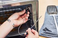 A person placing a device into the KitchenAid Dual Convection Countertop Oven with Air Fryer