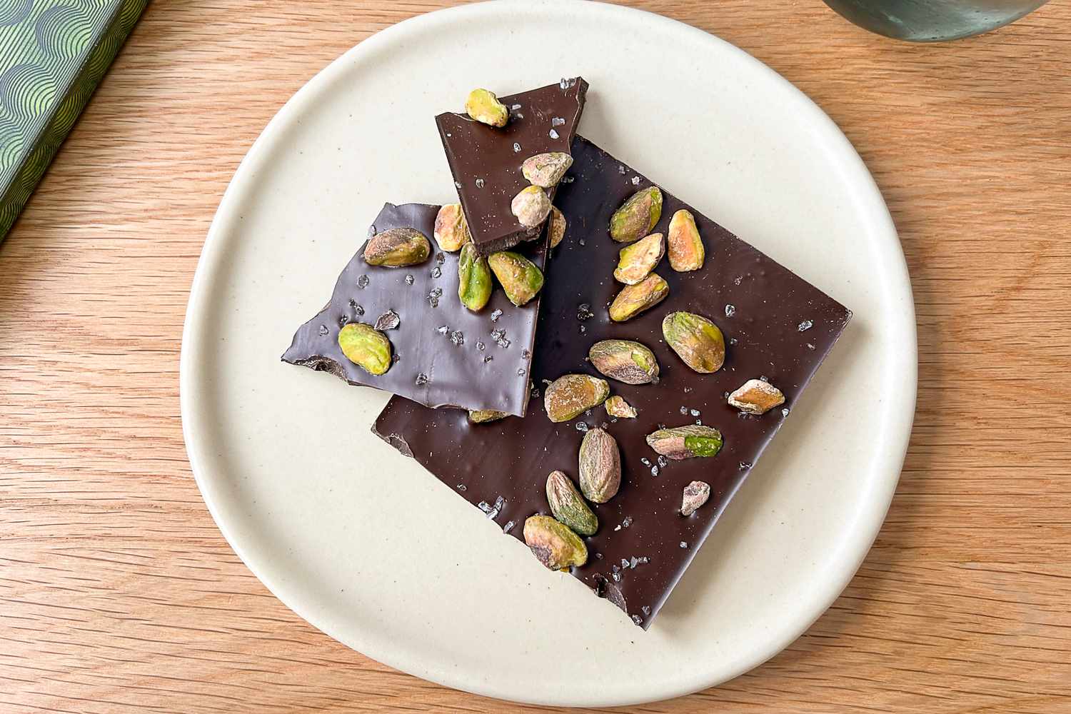 Pieces of a Compartés Salted Pistachio Chocolate Bar on a white plate