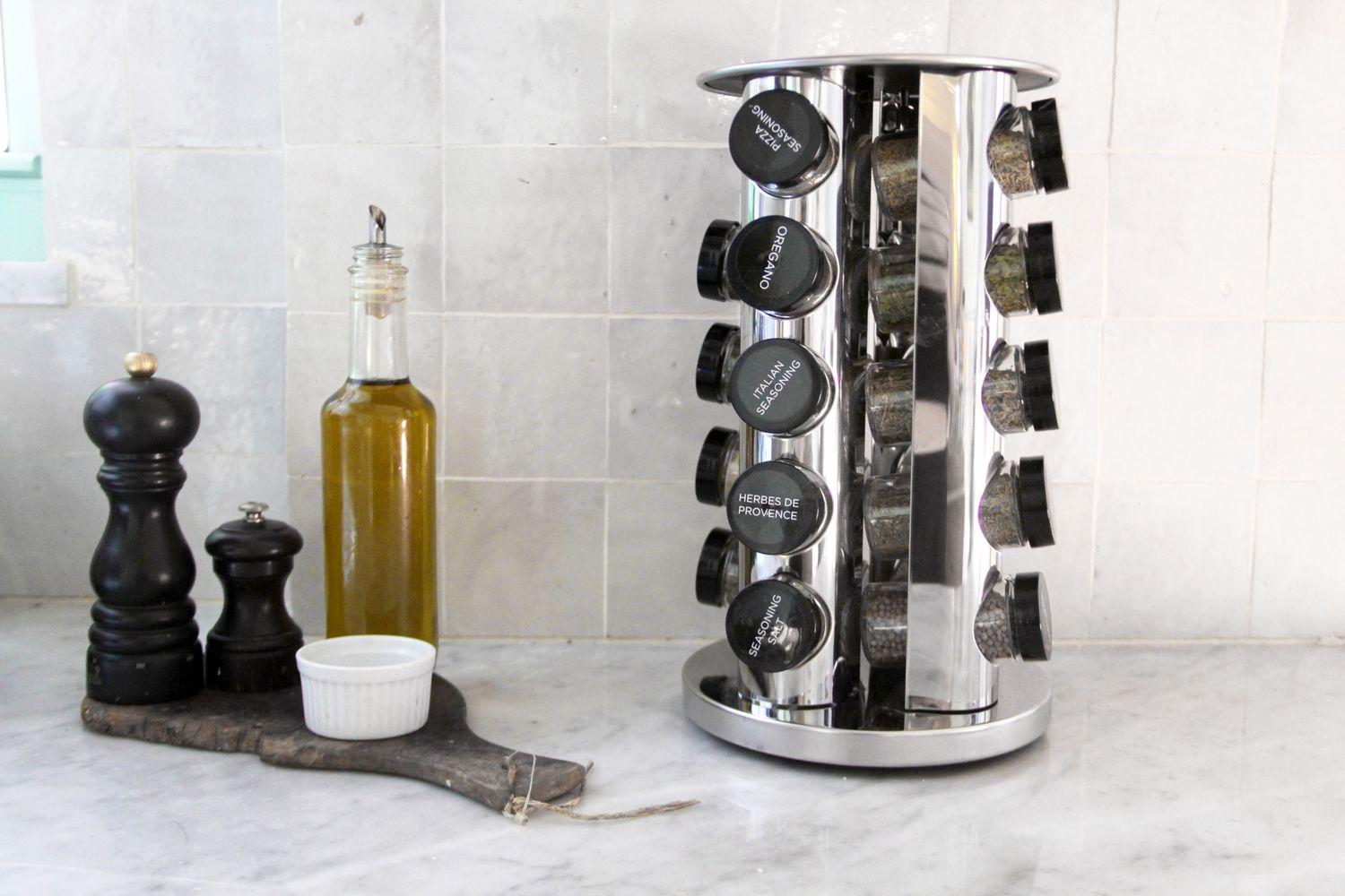 A counter with a spice rack oil bottle and pepper shakers arranged together