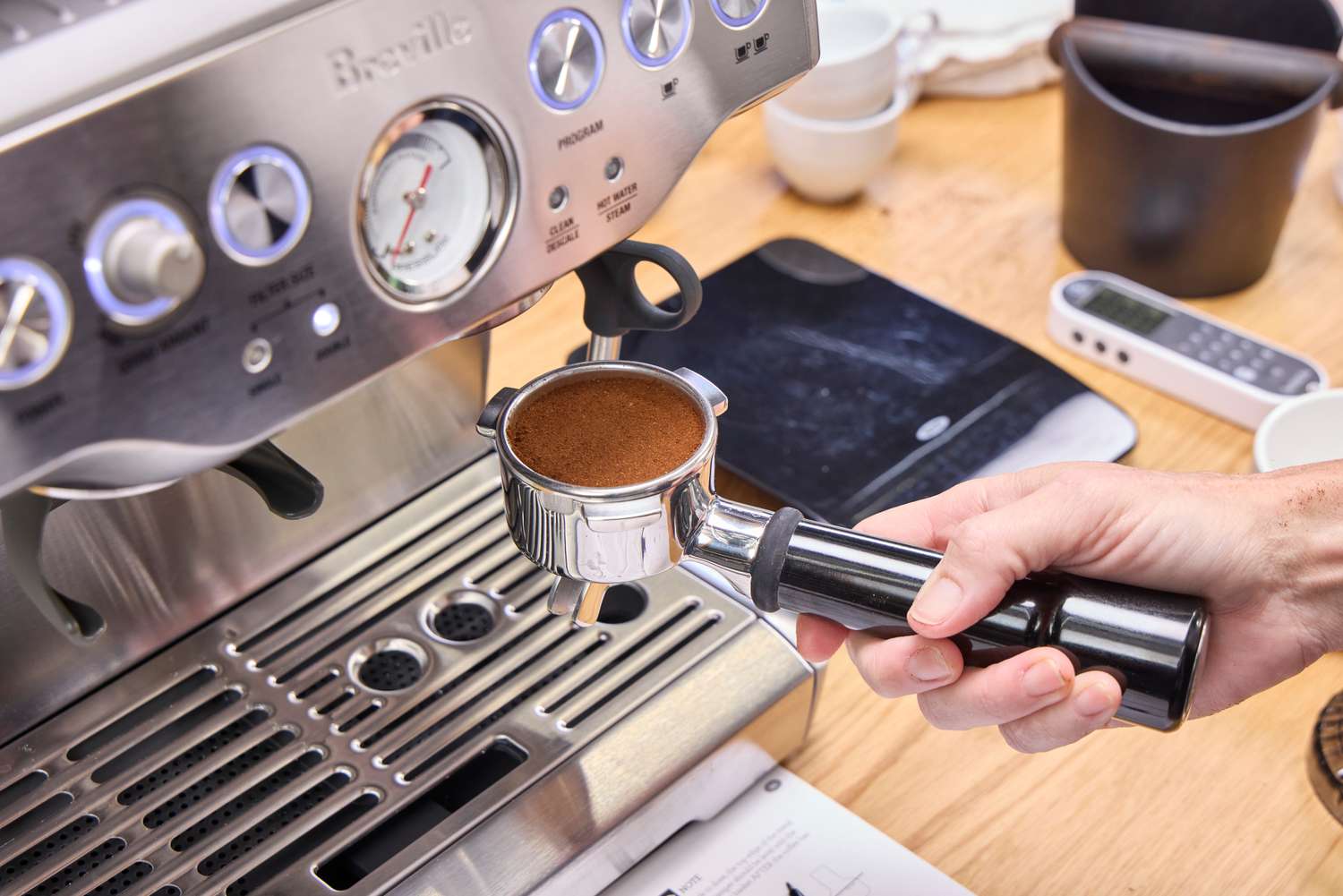 A person places a portafilter filled with coffee grounds into the Breville The Barista Express Espresso Machine