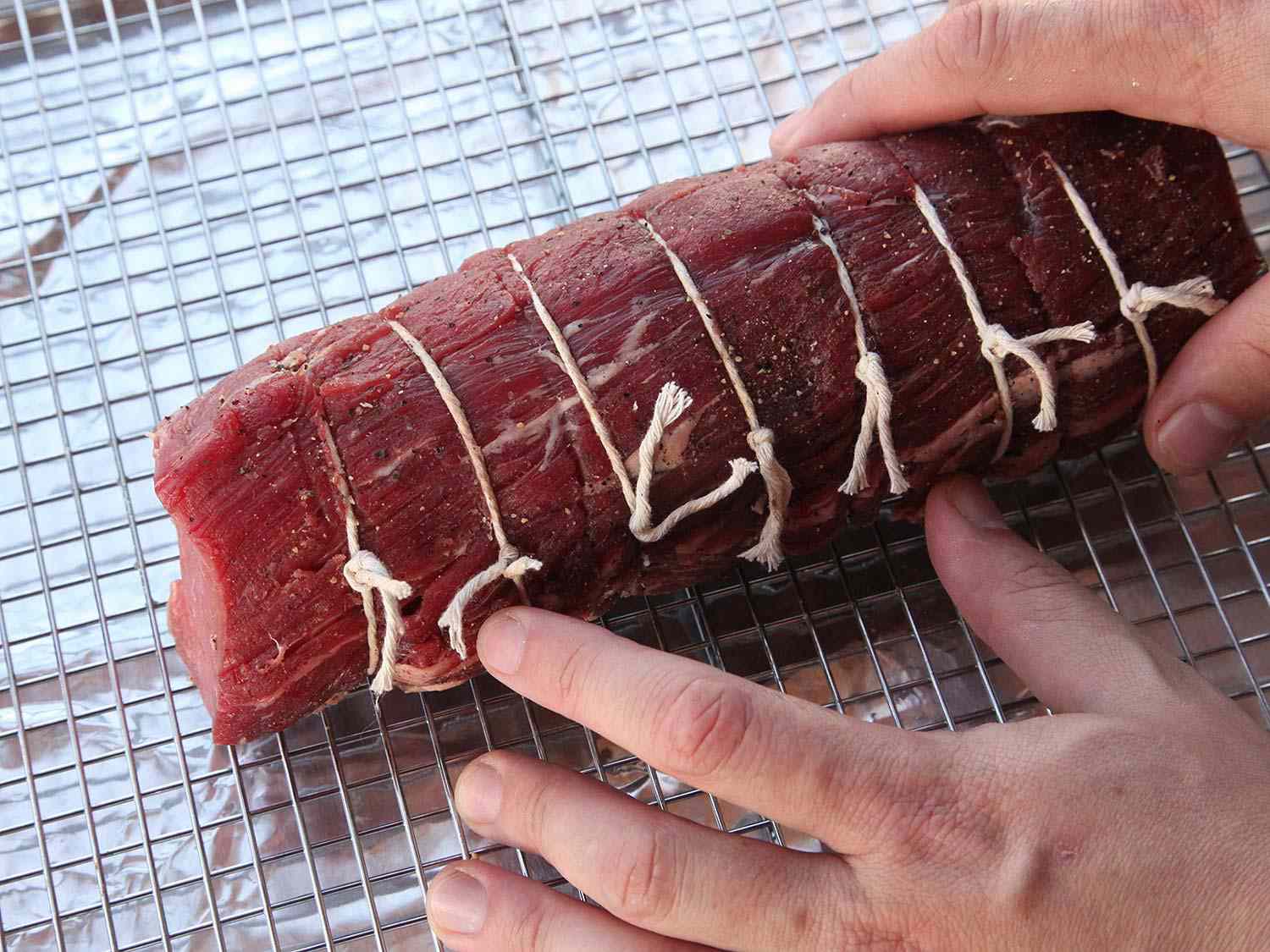 Placing a center cut beef tenderloin roast on a wire rack inside a baking sheet