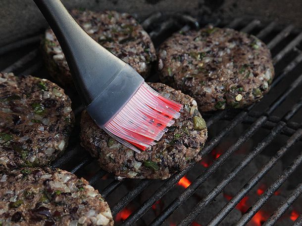 Brushing grilled black bean burgers with oil.