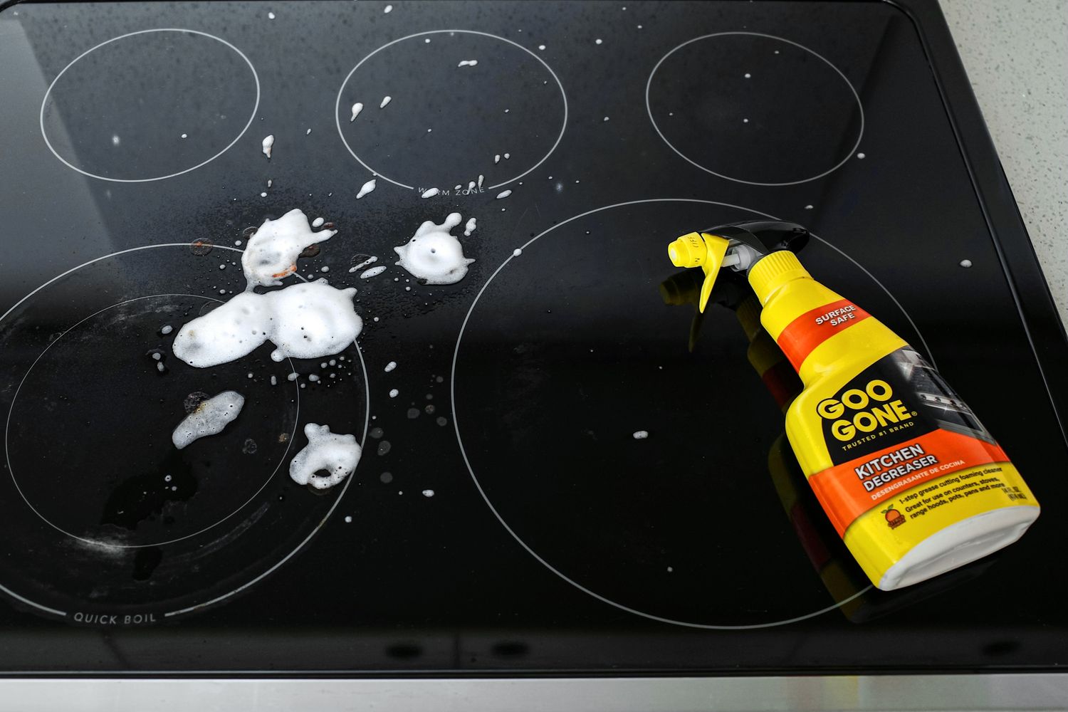 Electric stovetop with soapy residue and a bottle of Goo Gone kitchen degreaser