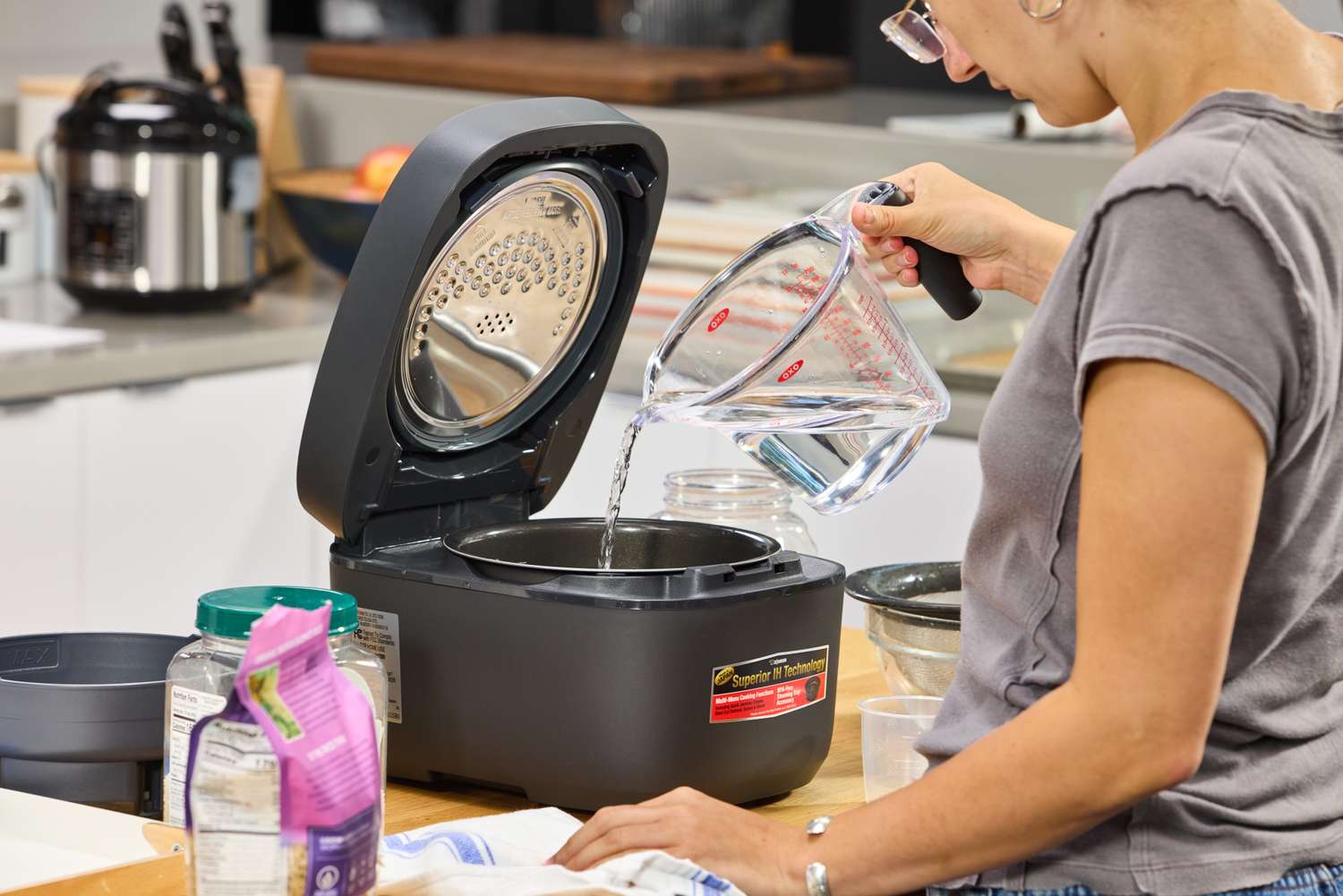 A person pours water into the Zojirushi NW-QAC10 Induction Heating Rice Cooker & Warmer