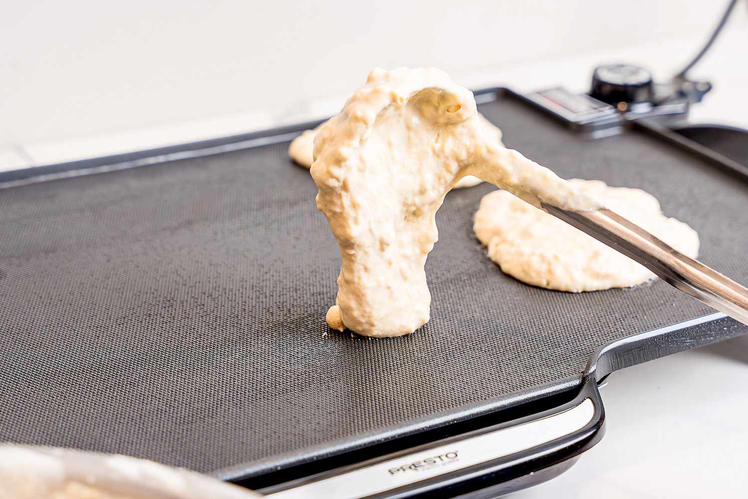 Pancake batter being added to an electric griddle