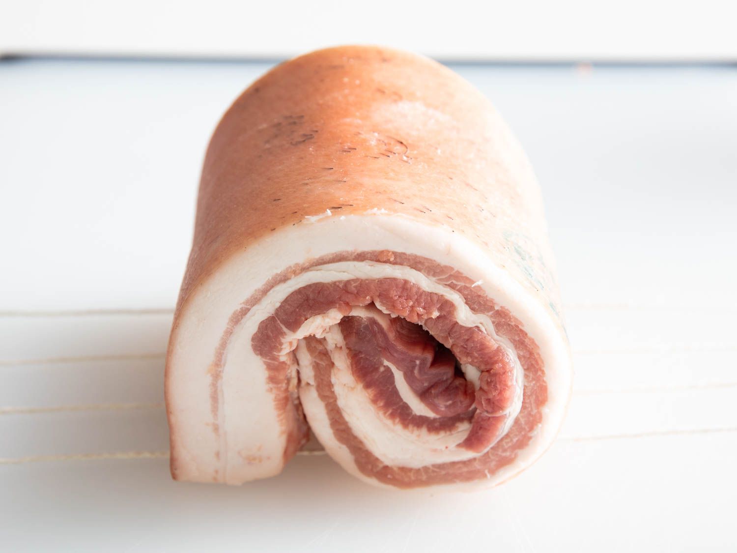 Front view of a rolled up slab of skin-on pork belly