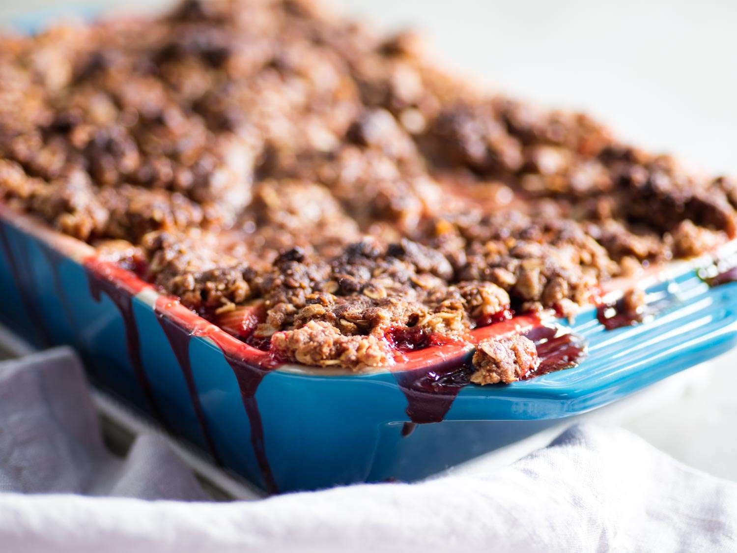 A finished strawberry-rhubarb crisp in a blue ceramic baking dish