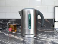 breville soft top electric kettle on countertop with cup of tea behind it