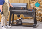 A person standing in front of the Traeger Woodridge pellet grill on a patio