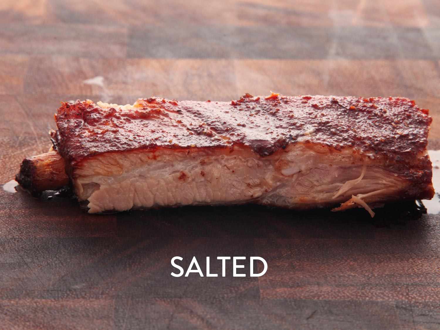 A salted pork rib cooked sous vide, resting on a wooden surface.
