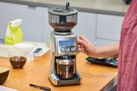 A person grinds coffee beans in the Breville The Smart Grinder Pro