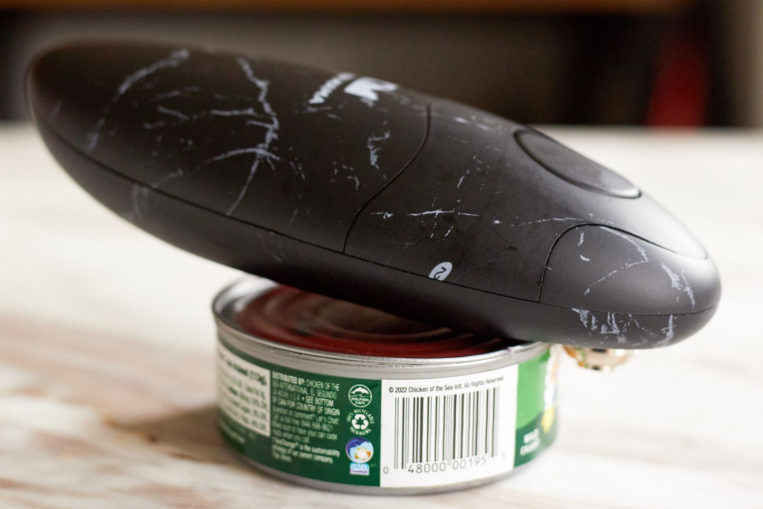 The Kitchen Mama Electric Can Opener on a small can on a marble countertop