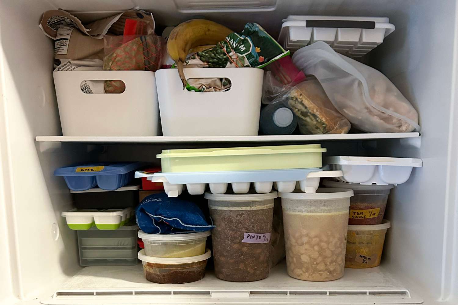 Various ice cube trays squeezed into a packed freezer.