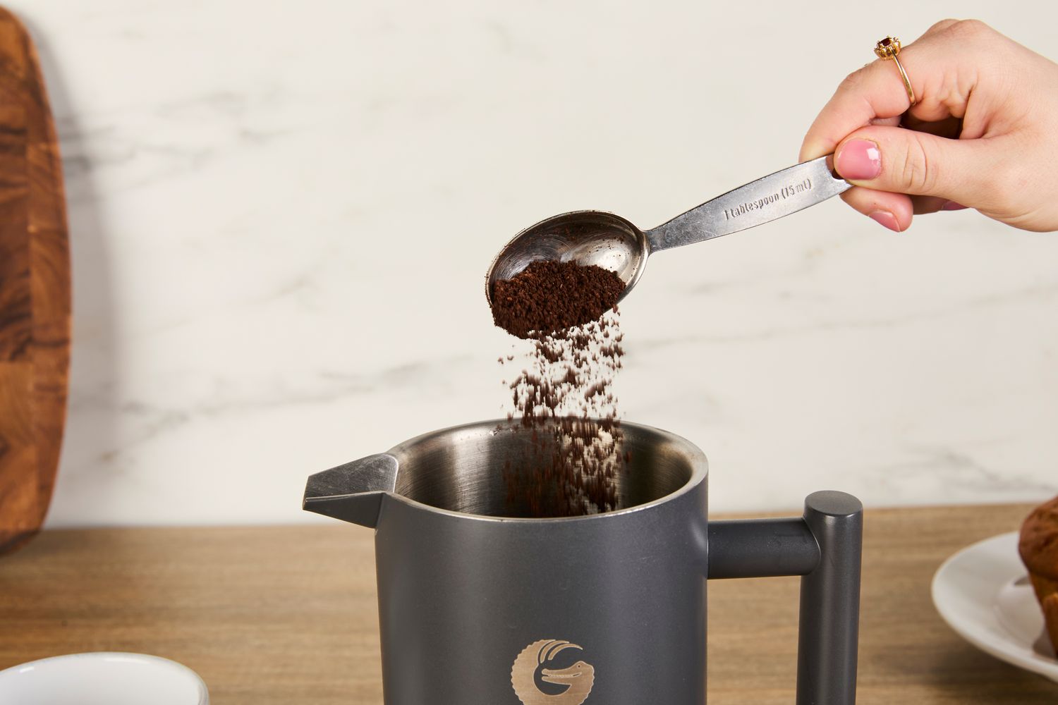 A person adding coffee grounds to the Coffee Gator French press.