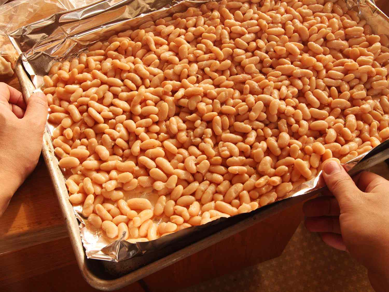 White beans spread on a foil-lined baking sheet.