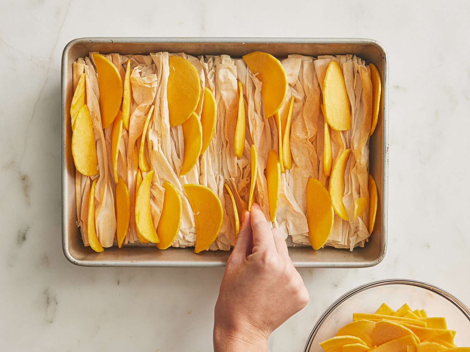 Tucking butternut squash into fold of crinkle dough in a sheet pan 