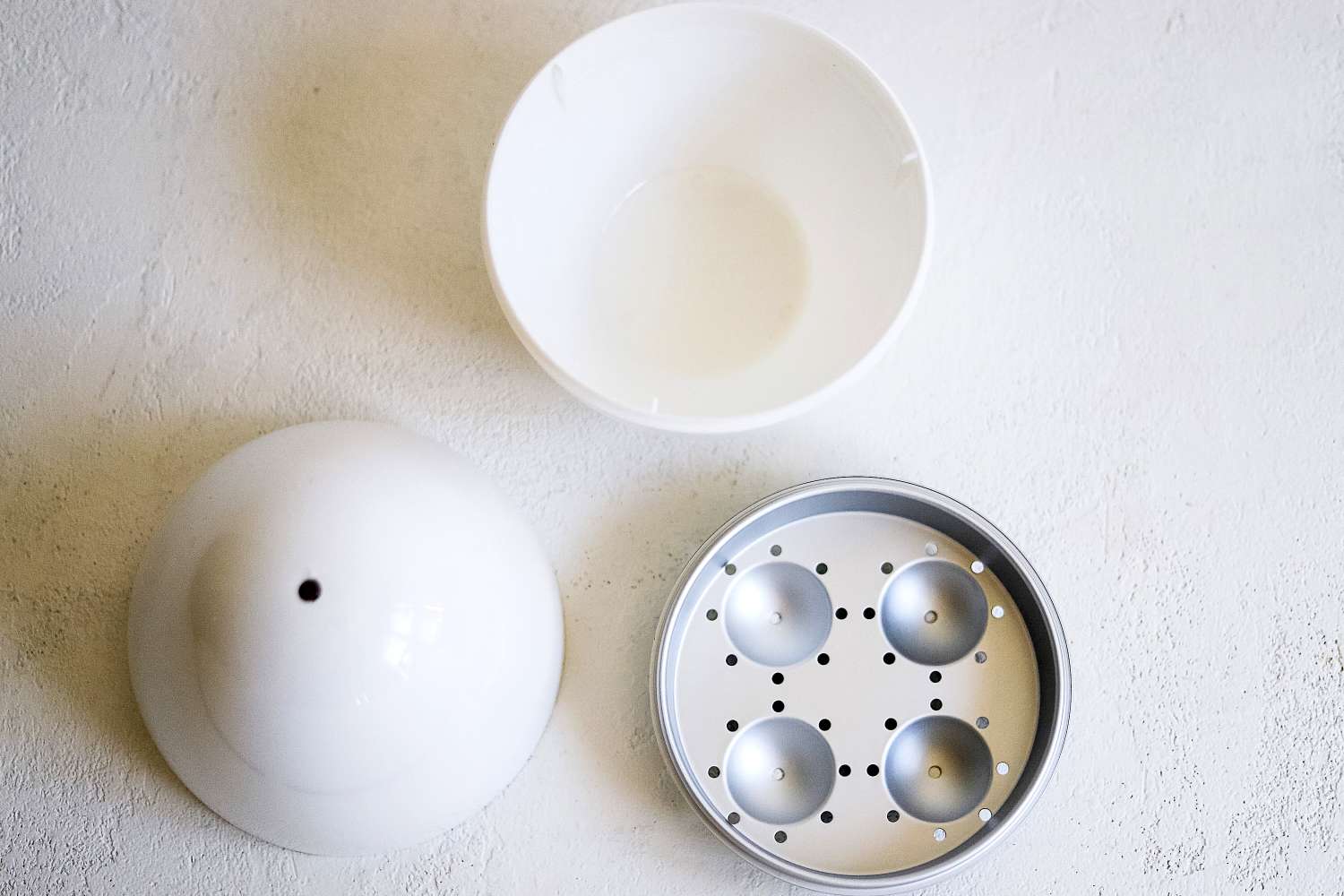 All of the parts of the Nordic Ware Egg Boiler on a white surface