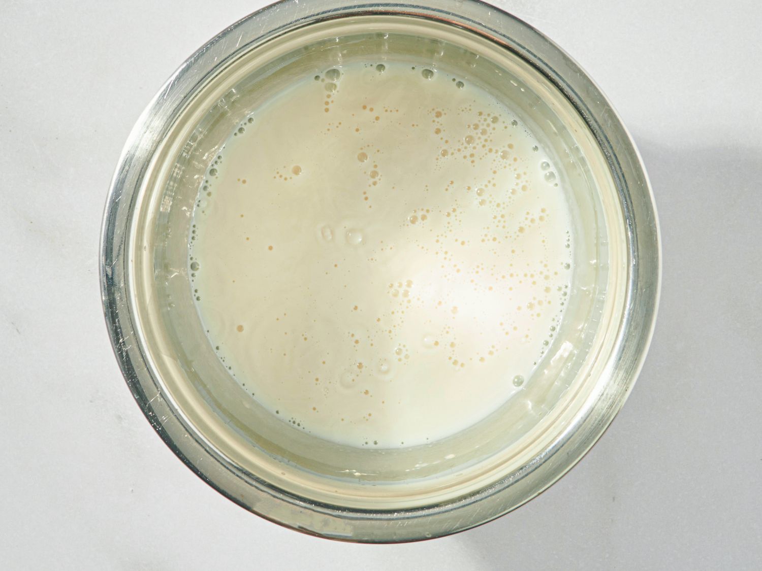 A metal bowl containing a smooth liquid mixture viewed from above