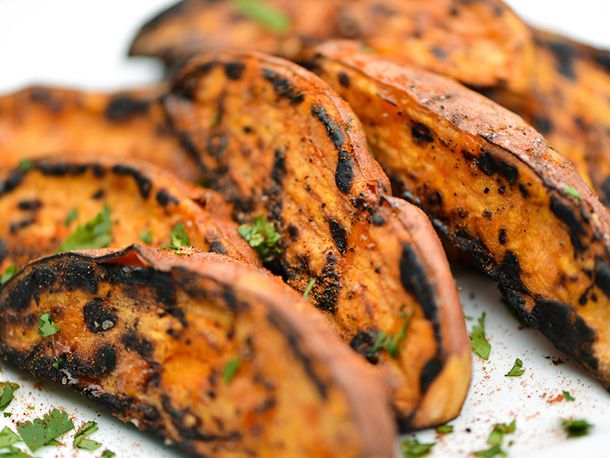 Finished sweet potato wedges on a serving plate, sprinkled with herbs and paprika. 