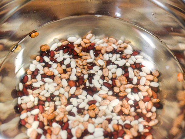 A bowl of mixed dried beans soaking in water.