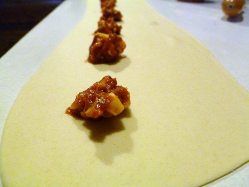 Thinly rolled dough with spoonfuls of filling for homemade pizza rolls