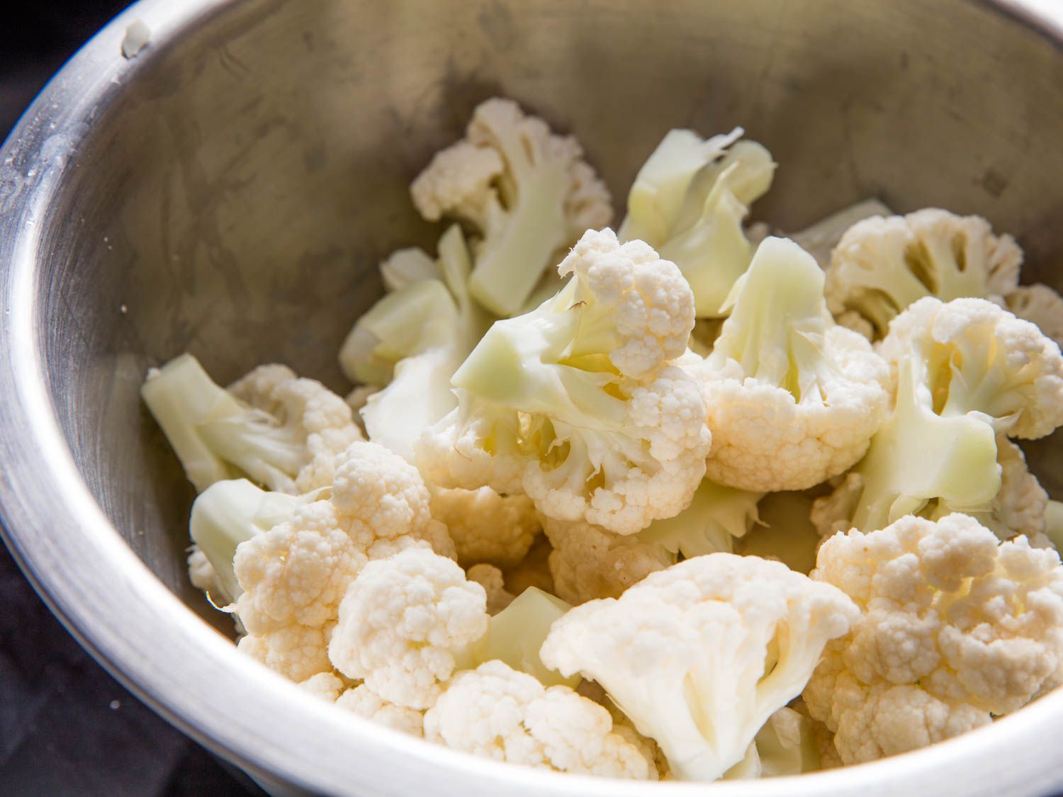 A stainless steel bowl of cauliflower florets.